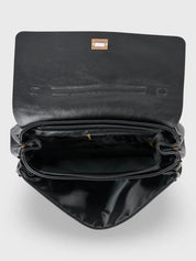 Black leather shoulder bag with structured shape, flap closure and slim top handle, photographed on a light background