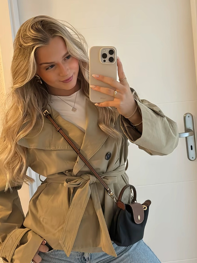 trench coat for women with a structured fit, high collar and dark buttons. Crafted from premium fabric, it highlights the waist and adds refined elegance to any autumn or winter outfit.