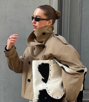 trench coat for women with a structured fit, high collar and dark buttons. Crafted from premium fabric, it highlights the waist and adds refined elegance to any autumn or winter outfit.