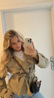 trench coat for women with a structured fit, high collar and dark buttons. Crafted from premium fabric, it highlights the waist and adds refined elegance to any autumn or winter outfit.