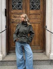 trench coat for women with a structured fit, high collar and dark buttons. Crafted from premium fabric, it highlights the waist and adds refined elegance to any autumn or winter outfit.