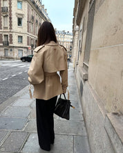 trench coat for women with a structured fit, high collar and dark buttons. Crafted from premium fabric, it highlights the waist and adds refined elegance to any autumn or winter outfit.