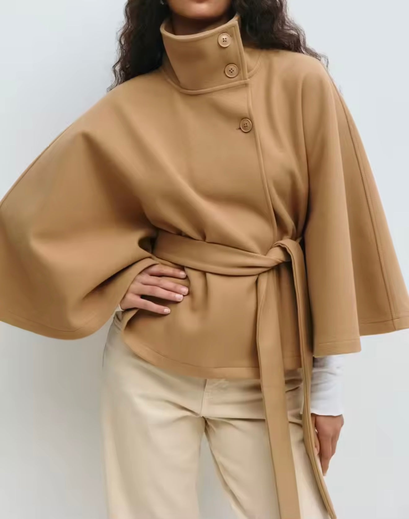 winter coat with high-neck collar, cape silhouette and adjustable waist belt. A chic belted jacket combining elegance, comfort and versatile seasonal style.