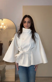 High-Neck Belted Cape Jacket in camel wool blend. Poncho-inspired autumn/winter coat with high-neck collar, cape silhouette and adjustable waist belt. A chic belted jacket combining elegance, comfort and versatile seasonal style.