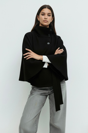 High-Neck Belted Cape Jacket in camel wool blend. Poncho-inspired autumn/winter coat with high-neck collar, cape silhouette and adjustable waist belt. A chic belted jacket combining elegance, comfort and versatile seasonal style.