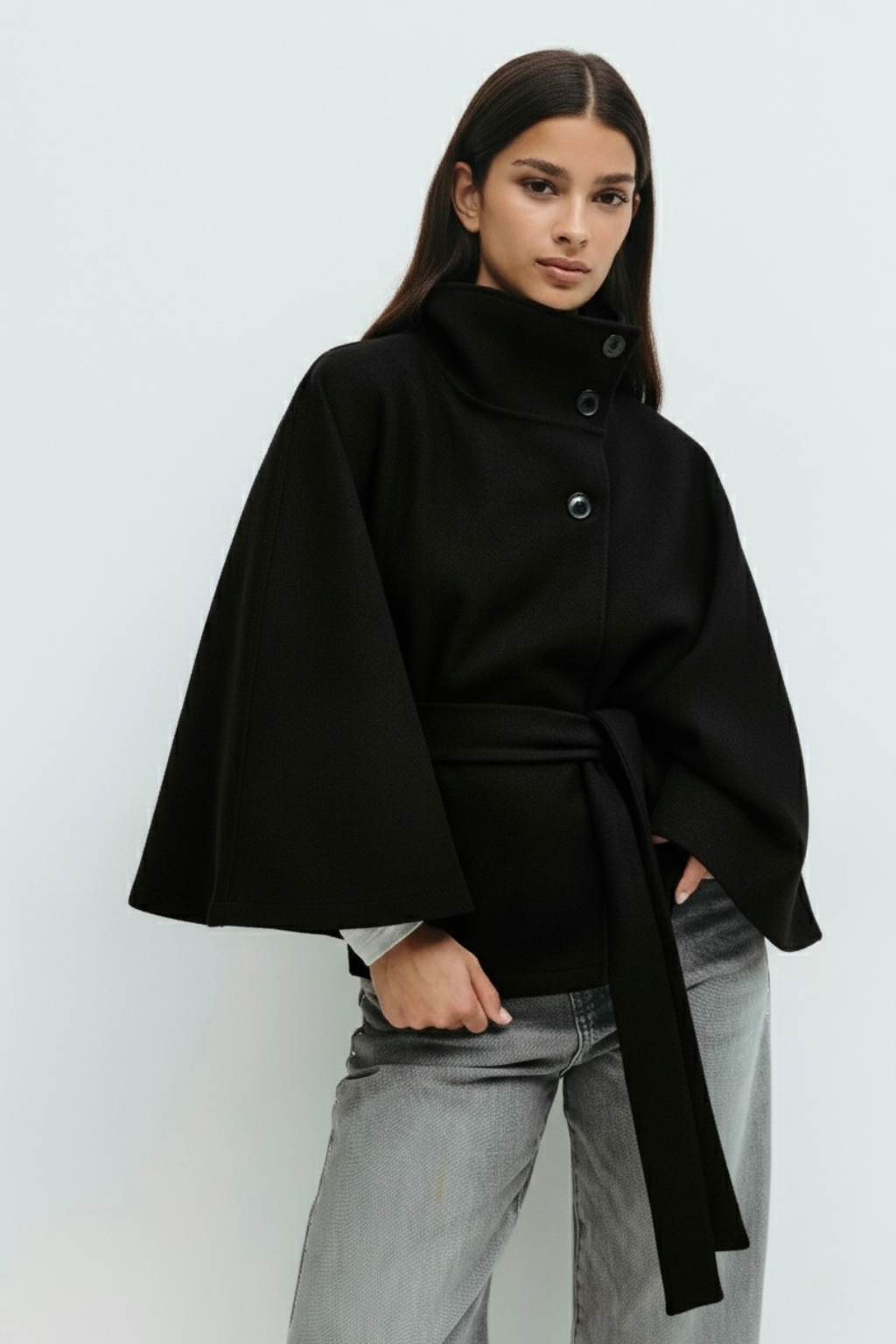 High-Neck Belted Cape Jacket in camel wool blend. Poncho-inspired autumn/winter coat with high-neck collar, cape silhouette and adjustable waist belt. A chic belted jacket combining elegance, comfort and versatile seasonal style.