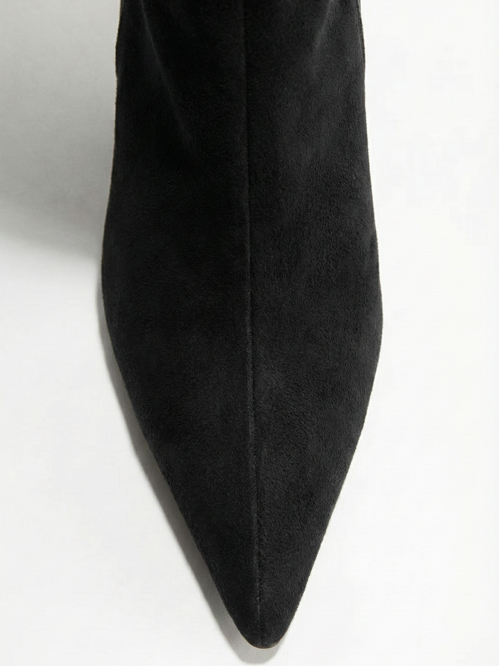 Black knee-high boot with a smooth suede-like finish, pointed toe, discreet low block heel, straight shaft design, and a slim metallic buckle detail at the top.