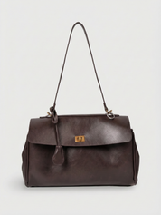 Dark brown leather shoulder bag with structured shape, flap closure and slim top handle, photographed on a light background