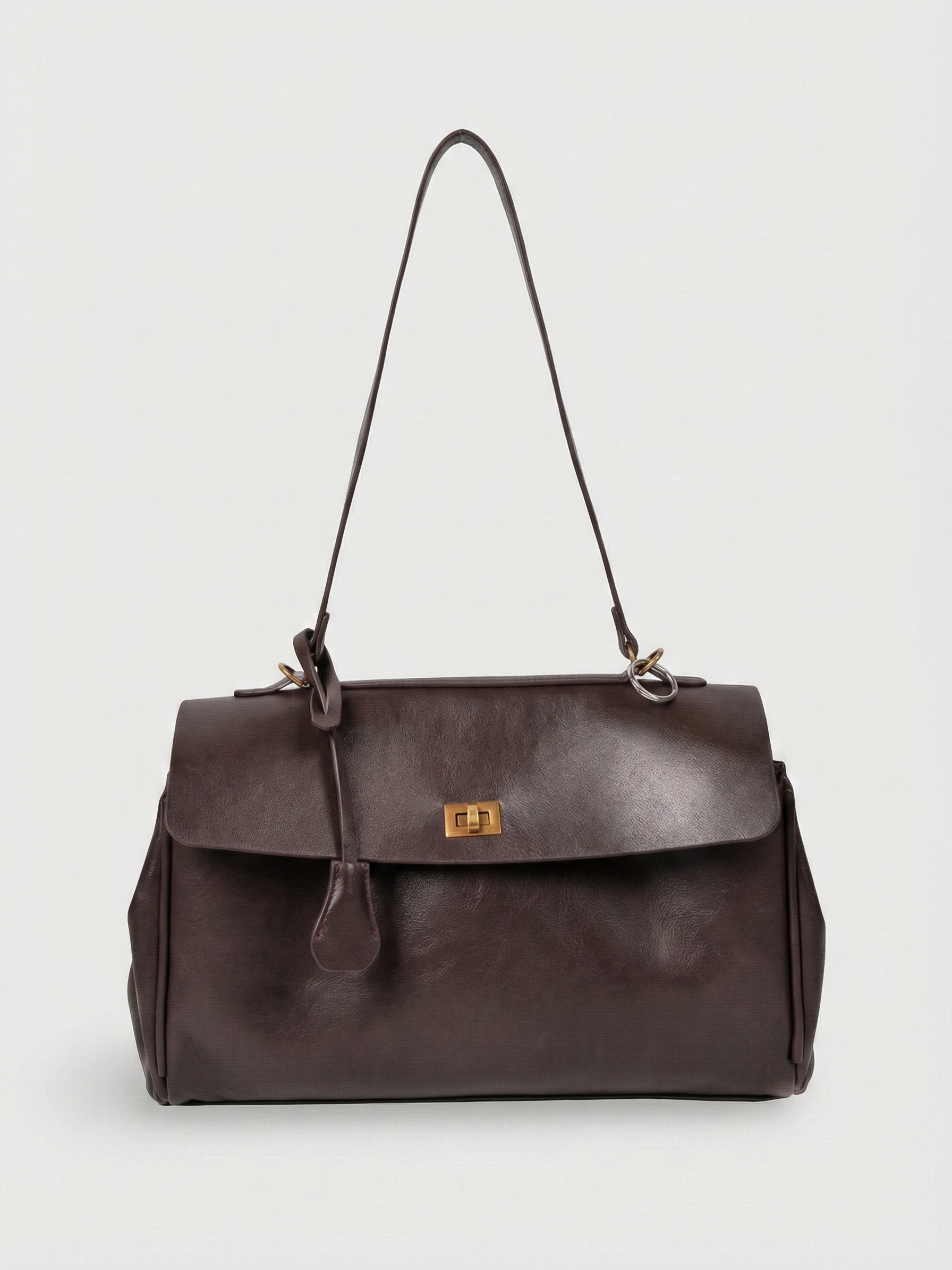 Dark brown leather shoulder bag with structured shape, flap closure and slim top handle, photographed on a light background