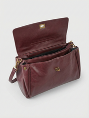 Burgundy leather shoulder bag with structured shape, flap closure and slim top handle, photographed on a light background