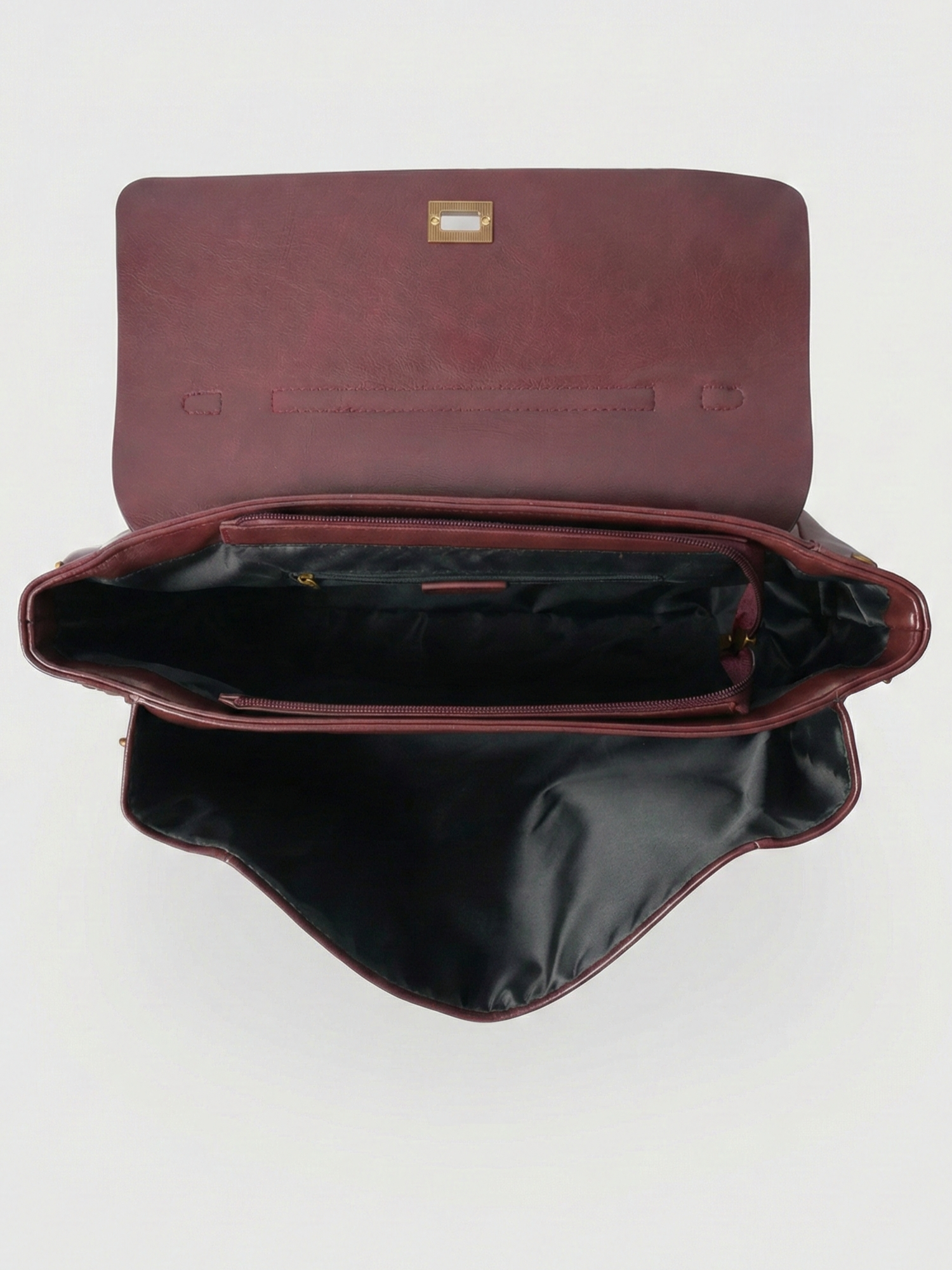 Burgundy leather shoulder bag with structured shape, flap closure and slim top handle, photographed on a light background