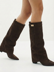Brown knee-high boot with a smooth suede-like finish, pointed toe, discreet low block heel, straight shaft design, and a slim metallic buckle detail at the top.