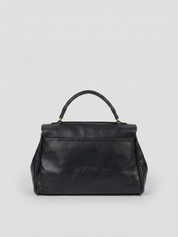 Black leather shoulder bag with structured shape, flap closure and slim top handle, photographed on a light background