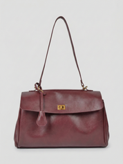 Burgundy leather shoulder bag with structured shape, flap closure and slim top handle, photographed on a light background