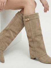 Apricot knee-high boot with a smooth suede-like finish, pointed toe, discreet low block heel, straight shaft design, and a slim metallic buckle detail at the top.