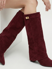 Burgundy knee-high boot with a smooth suede-like finish, pointed toe, discreet low block heel, straight shaft design, and a slim metallic buckle detail at the top.