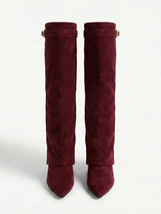Burgundy knee-high boot with a smooth suede-like finish, pointed toe, discreet low block heel, straight shaft design, and a slim metallic buckle detail at the top.