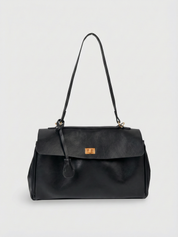 Black leather shoulder bag with structured shape, flap closure and slim top handle, photographed on a light background