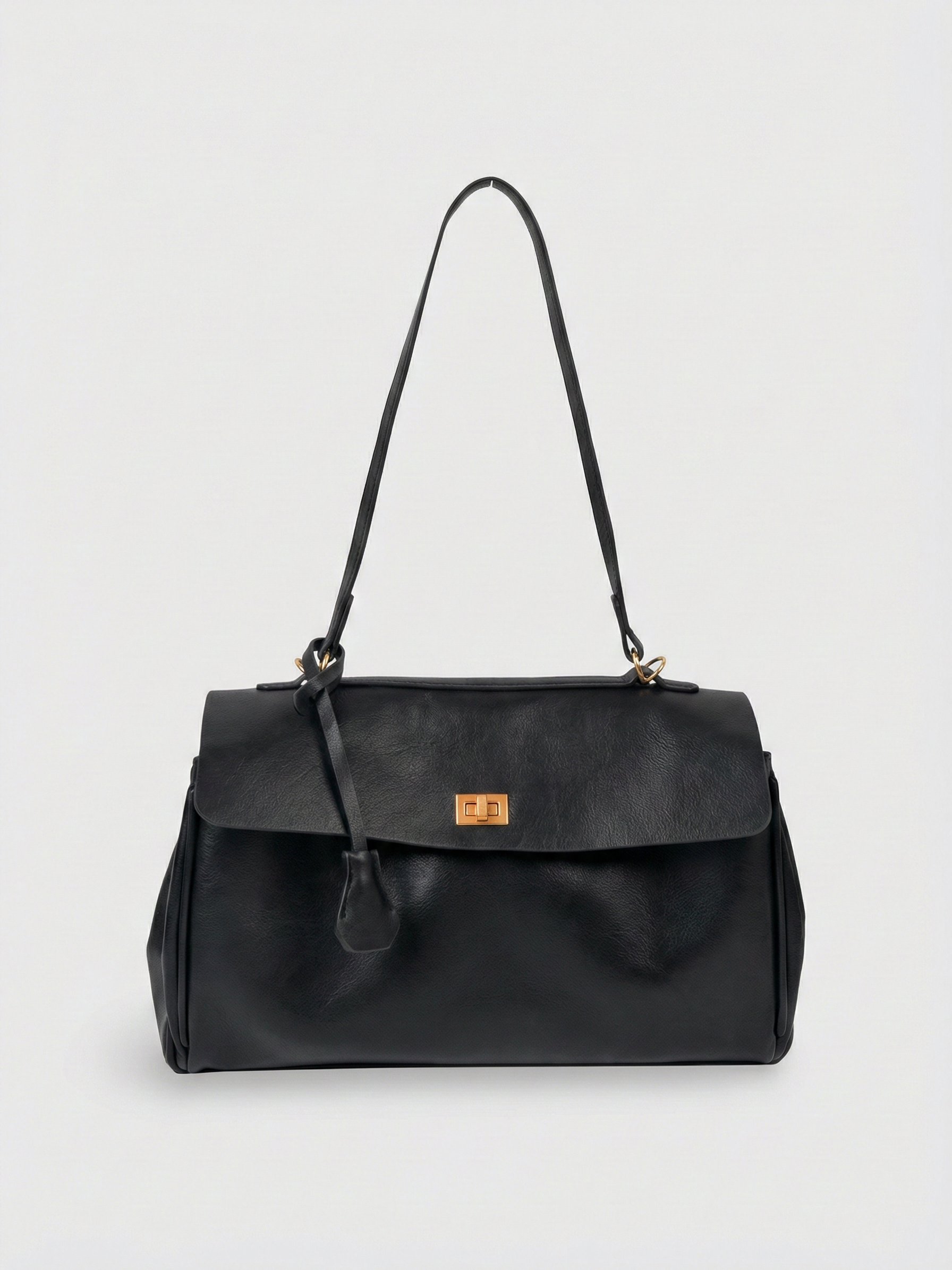 Black leather shoulder bag with structured shape, flap closure and slim top handle, photographed on a light background