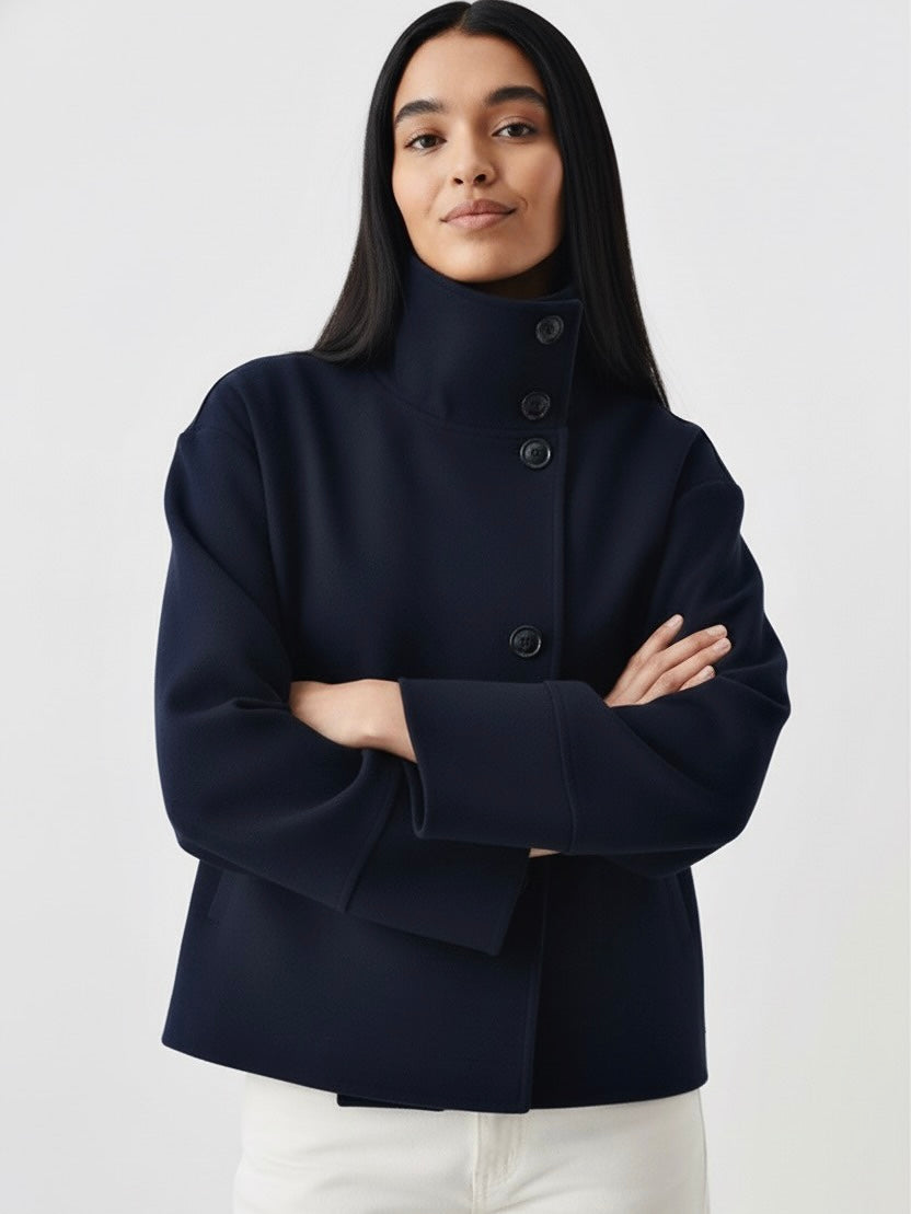 Black high-neck jacket with asymmetrical buttons and structured silhouette, featuring wide sleeves and a minimalist design for modern everyday styling.