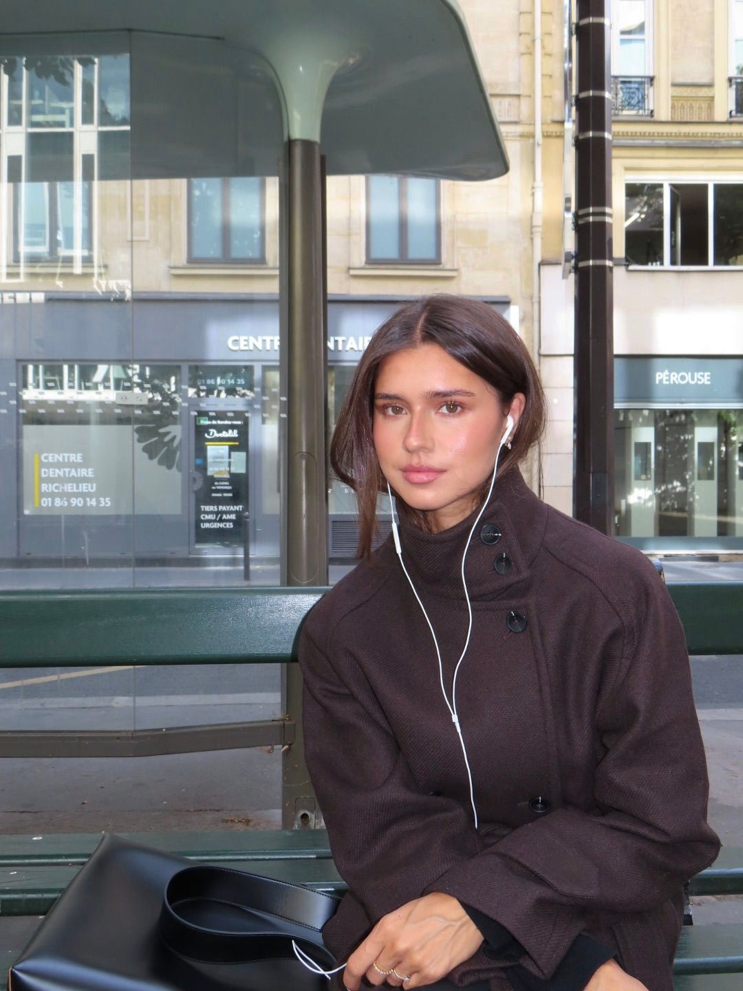 Black high-neck jacket with asymmetrical buttons and structured silhouette, featuring wide sleeves and a minimalist design for modern everyday styling.