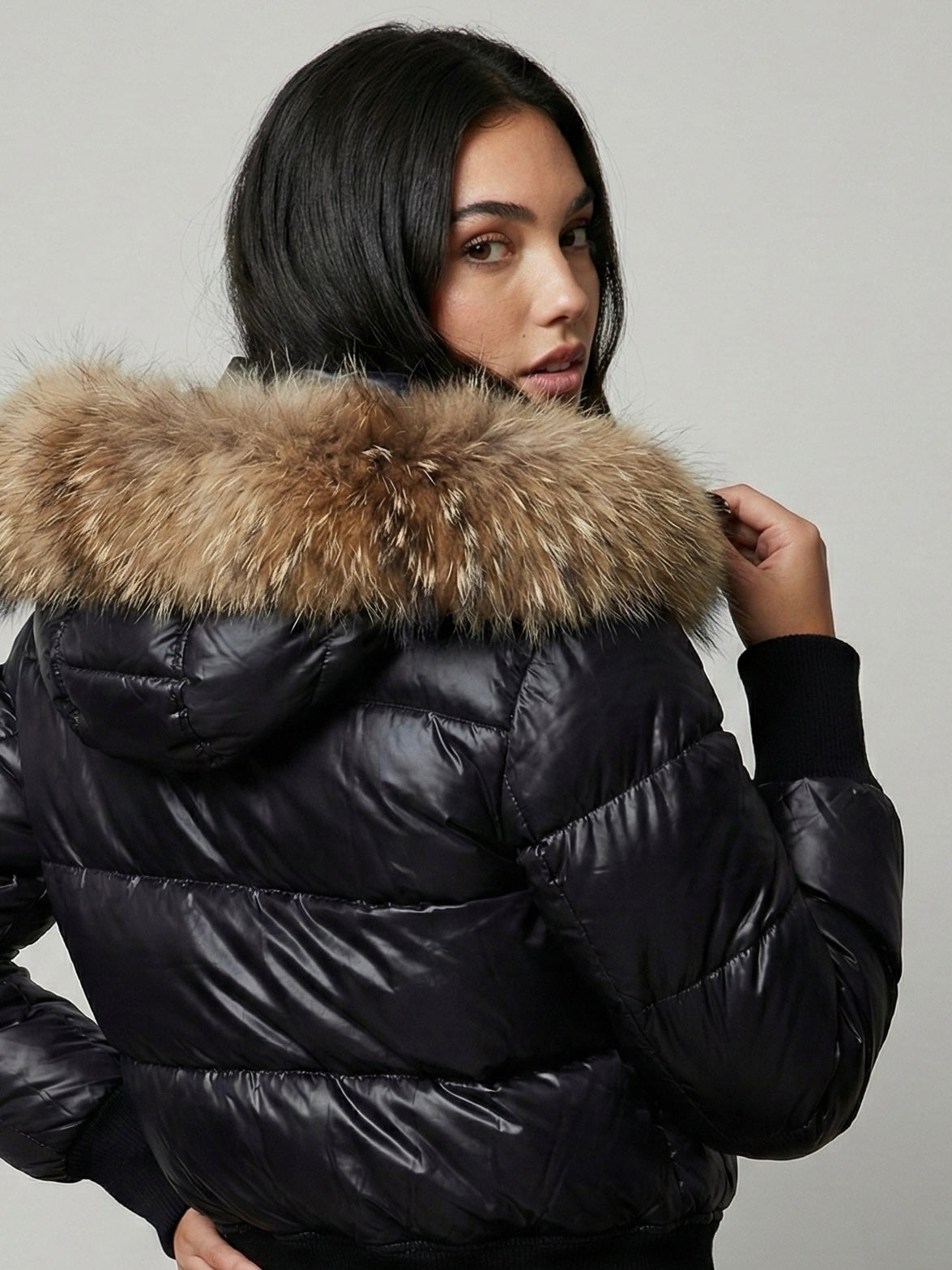 Black puffer jacket with padded quilted design and a plush faux fur hood. Features zip fastening, fitted waist and long sleeves, offering warmth and stylish winter protection.
