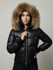Black puffer jacket with padded quilted design and a plush faux fur hood. Features zip fastening, fitted waist and long sleeves, offering warmth and stylish winter protection.