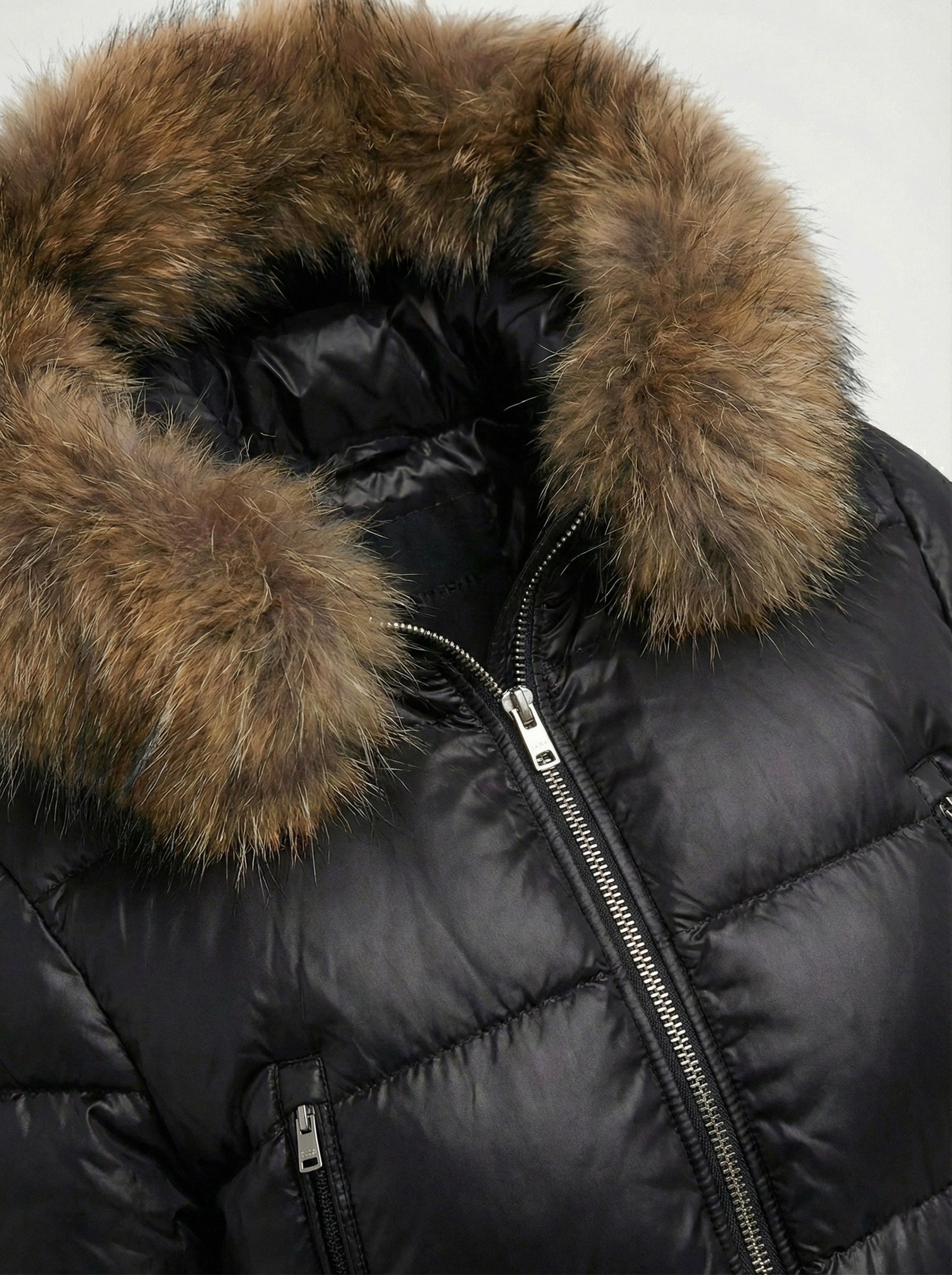 Black puffer jacket with padded quilted design and a plush faux fur hood. Features zip fastening, fitted waist and long sleeves, offering warmth and stylish winter protection.