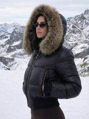 Black puffer jacket with padded quilted design and a plush faux fur hood. Features zip fastening, fitted waist and long sleeves, offering warmth and stylish winter protection.