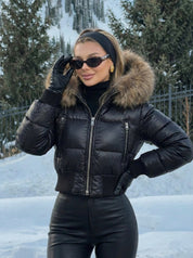 Black puffer jacket with padded quilted design and a plush faux fur hood. Features zip fastening, fitted waist and long sleeves, offering warmth and stylish winter protection.