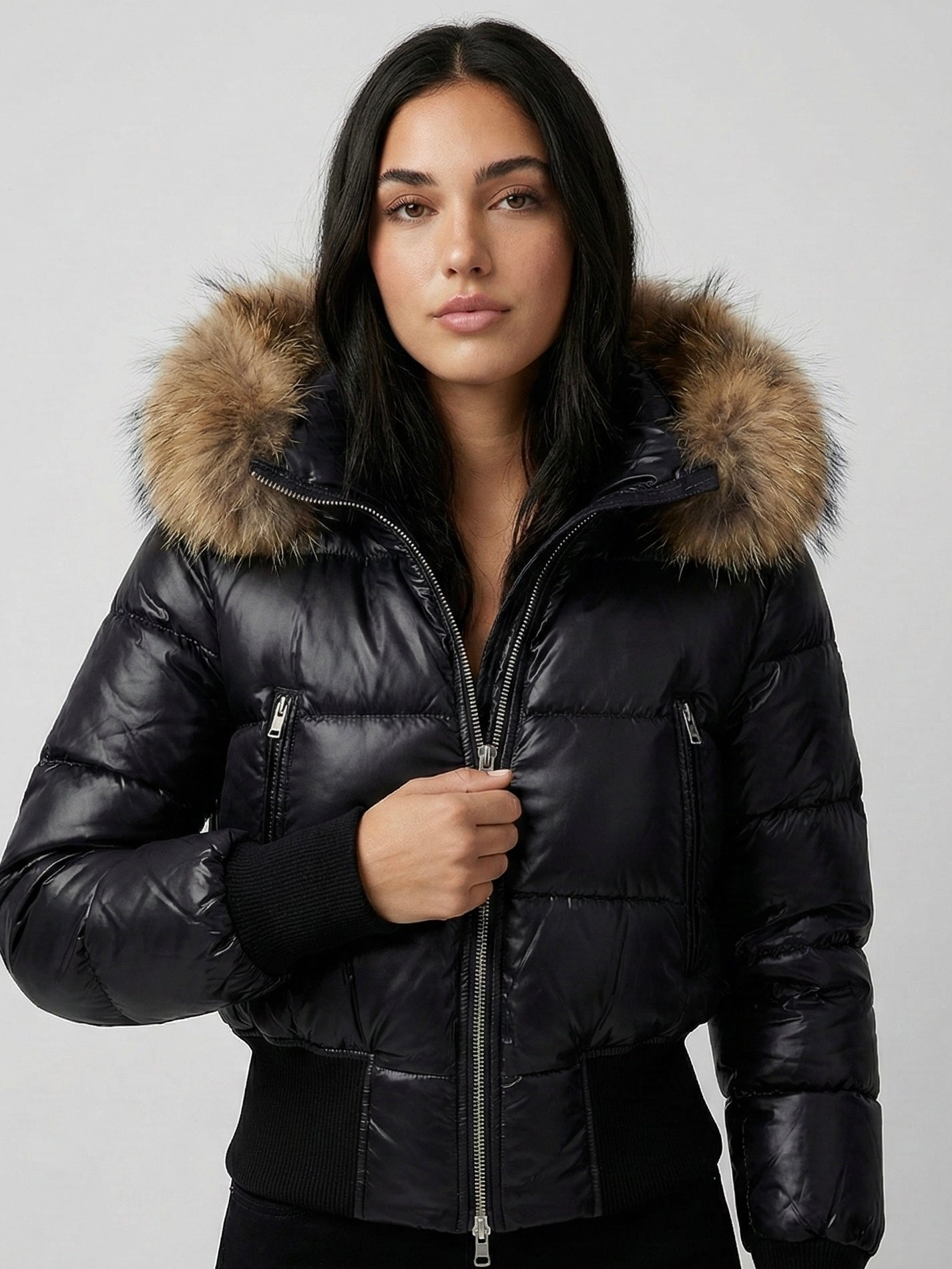 Black puffer jacket with padded quilted design and a plush faux fur hood. Features zip fastening, fitted waist and long sleeves, offering warmth and stylish winter protection.
