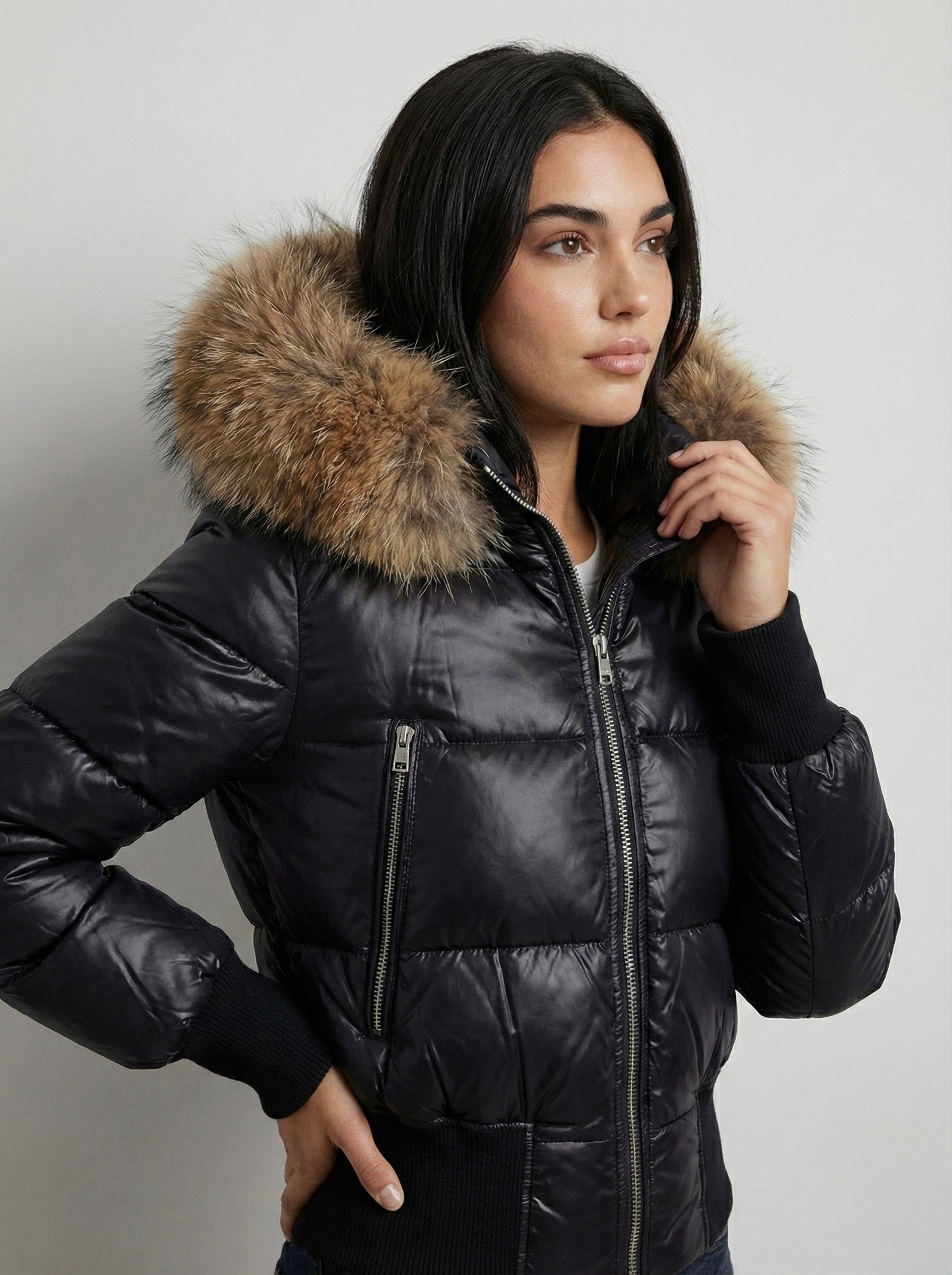 Black puffer jacket with padded quilted design and a plush faux fur hood. Features zip fastening, fitted waist and long sleeves, offering warmth and stylish winter protection.
