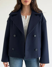 Navy double-breasted short jacket featuring a structured fit, wide lapel collar and clean tailoring. A versatile women’s jacket ideal for autumn and winter everyday wear.