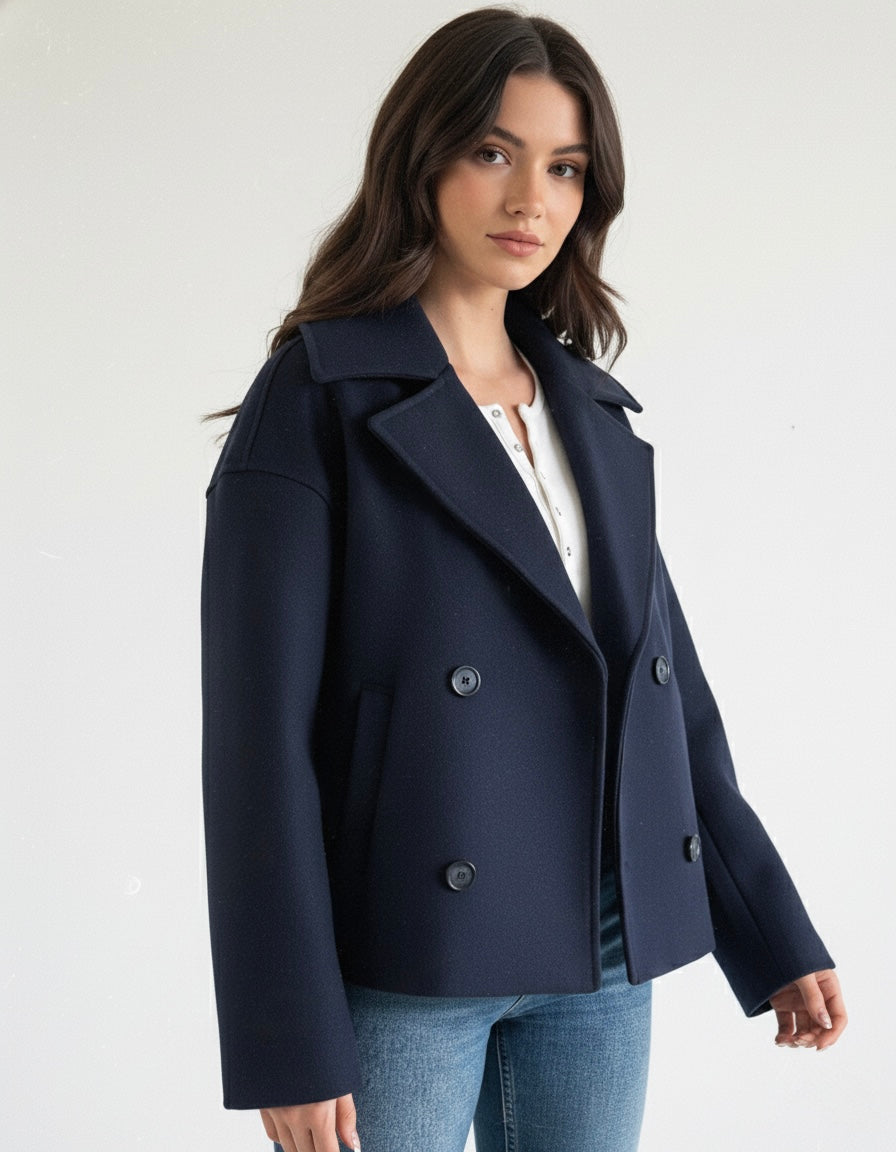Navy double-breasted short jacket featuring a structured fit, wide lapel collar and clean tailoring. A versatile women’s jacket ideal for autumn and winter everyday wear.