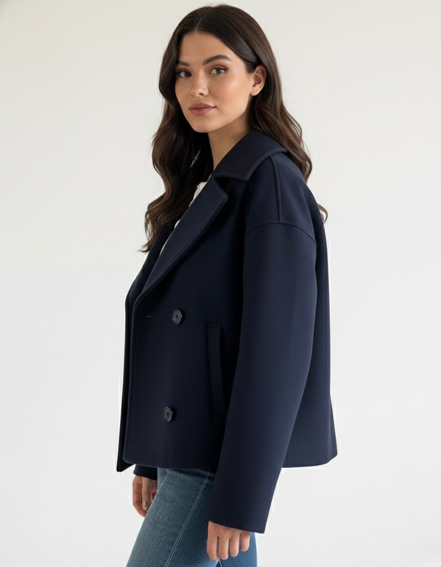 Navy double-breasted short jacket featuring a structured fit, wide lapel collar and clean tailoring. A versatile women’s jacket ideal for autumn and winter everyday wear.