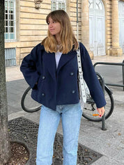 Navy double-breasted short jacket featuring a structured fit, wide lapel collar and clean tailoring. A versatile women’s jacket ideal for autumn and winter everyday wear.